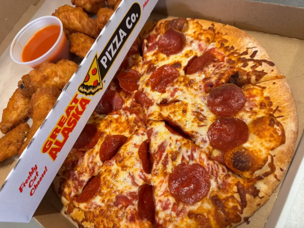 Pepperoni pizza with chicken wings and dipping sauce in a Great Alaska Pizza Co. box