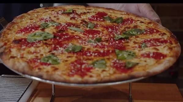 Tomato pie with basil on a metal riser at House of Fire Pizza, Fairbanks